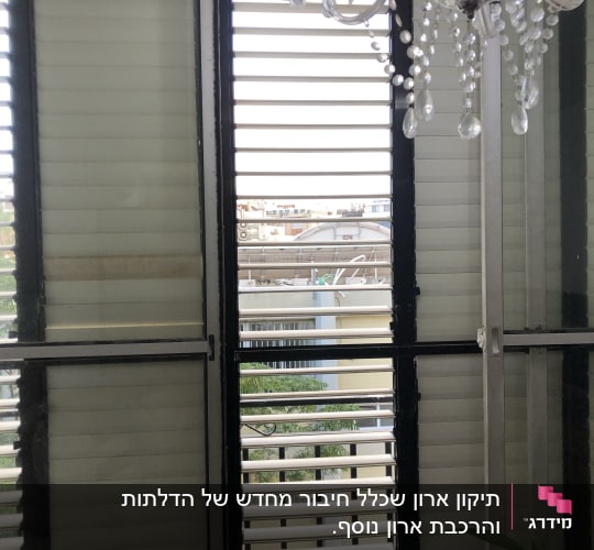 חלון עם תריסים פתוחים ונברשת זכוכית